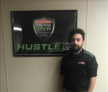 Tyler standing in front of a SERVPRO plaque in our office hallway.