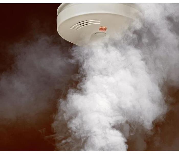 A smoke detector shrouded in smoke from below